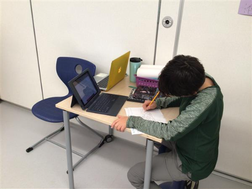 Student writing at table